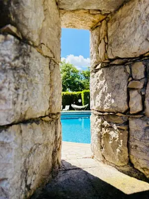 a view of a pool through a stone wall at Hacienda Provençale- Piscine, Pétanque et Plenitude in Saint-Jeannet