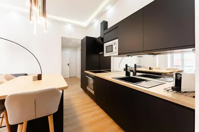 a kitchen with black cabinets and a wooden counter top at Ambiance cosy a la Niçoise in Nice