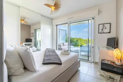 a bedroom with a bed and a balcony with a television at Azur Panoramique – Calme Vue Mer proche Nice in Saint-Laurent-du-Var