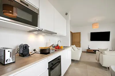 a kitchen with white cabinets and a living room at Modern Apartment With City View - Happy Rentals in Nice