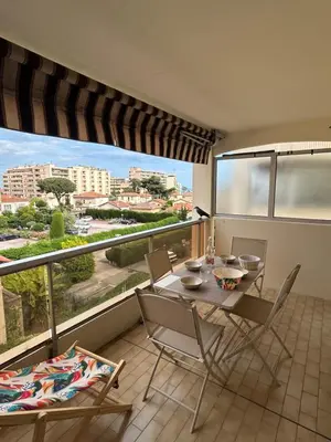 a balcony with a table and chairs and a large window at Appartement cosy à 200 m de la mer in Cagnes-sur-Mer