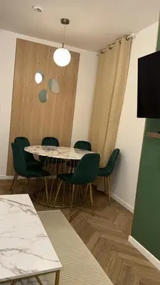 a dining room with a table and green chairs at MOON 25 in Nice