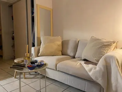 a living room with a white couch and a table at Studio 50M de la mer in Saint-Laurent-du-Var