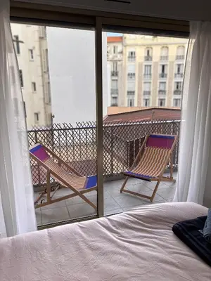 a bedroom with a bed and two chairs on a balcony at 