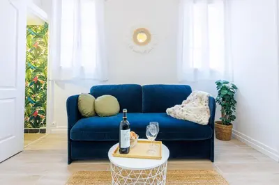 a blue couch in a living room with a bottle of wine at Charmant studio refait à neuf quartier du port in Nice
