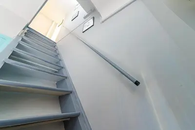 a staircase in a building with a clock on the wall at Charmant studio refait à neuf quartier du port in Nice