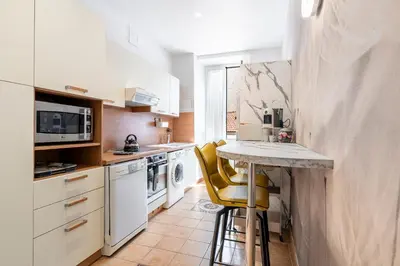 a kitchen with a counter and yellow bar stools at Appartement 2 chambres proche plage climatisé in Nice