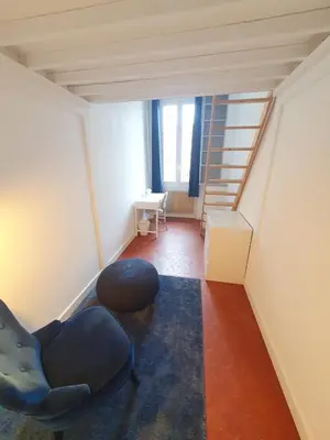 a living room with a stair case and a chair at Superbe appartement niçois in Nice