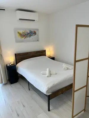 a bedroom with a bed with white sheets and two lamps at Riviera Retreat - Steps to Beach & Shops, Balcony & AC in Saint-Laurent-du-Var