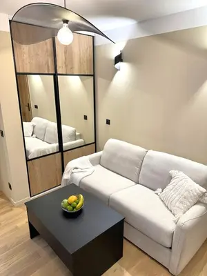 a living room with a couch and a table and a mirror at Studio Californien à deux pas de la plage in Nice