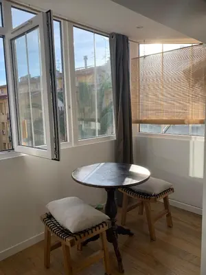 a table and chairs in a room with windows at Grand studio Zen à côté de la promenade des Anglais in Nice