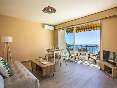 a living room with a couch and a tv and a balcony at Apartment Cros de Cagnes-2 by Interhome in Cagnes-sur-Mer