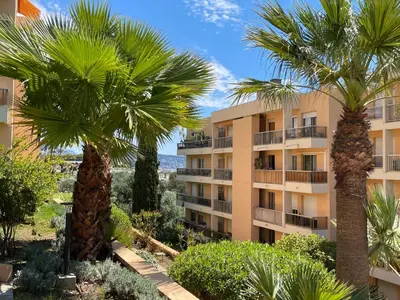 a building with palm trees in front of it at STUDIO BALCON CALME AVEC PARKING 5mn de la MER in Nice