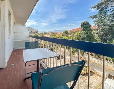 a balcony with a white table and chairs on it at Studio proche de la mer avec parking Cagnes-sur-Mer in Cagnes-sur-Mer