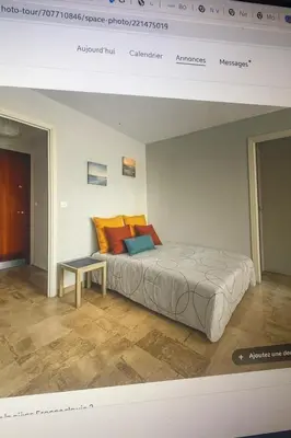 a bedroom with a bed with orange and blue pillows at Studio proche de la mer avec parking Cagnes-sur-Mer in Cagnes-sur-Mer