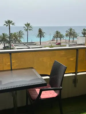 a table and chairs on a balcony with a view of the ocean at Appartement vue mer CALIFORNIE PROMENADE DES ANGLAIS in Nice