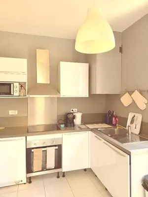 a kitchen with white cabinets and a pendant light at 3 pièces près du Port de Nice in Nice
