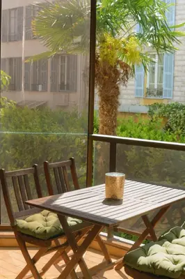 a wooden table and chairs on a balcony with a palm tree at Rivoli Center Terrasse Clim Parking in Nice