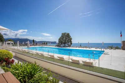 a swimming pool with chairs and the ocean in the background at ALTAIR AP4466 by RIVIERA HOLIDAY HOMES in Nice