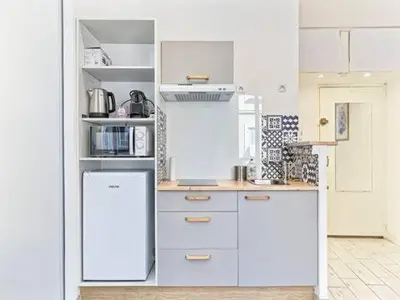 a kitchen with white cabinets and a refrigerator at Studio Hyper Centre - WIFI - Central in Nice