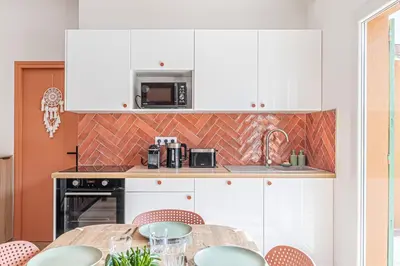 a kitchen with white cabinets and a table with chairs at Maison 6-7p, Terrasses, proche Plages, Nice Centre in Nice
