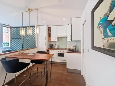 a kitchen with white cabinets and a wooden table and chairs at Nestor&Jeeves - REFLET DOR - Vieux Nice - Near beach in Nice