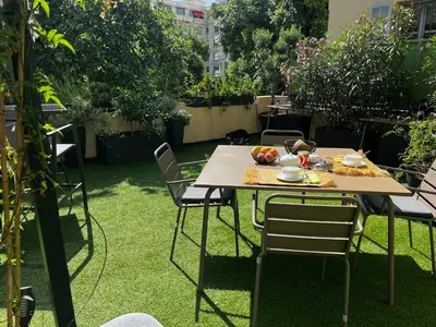 a table and chairs in a garden with grass at Chambre Vue Jardin Alsace Lorraine Victor Hugo in Nice