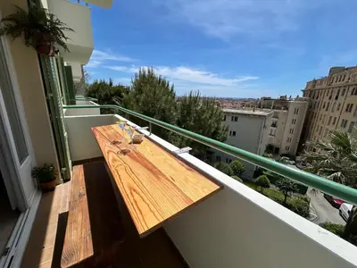 a wooden table on a balcony with a view at Cosy appartement en plein centre-ville dans un halo de verdure avec vue mer in Nice
