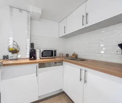 a white kitchen with white cabinets and a microwave at Havre de paix avec terrasse in La Gaude