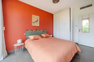 a bedroom with an orange wall and a bed at Maison niçoise vue dégagée avec jacuzzi privatif in Nice