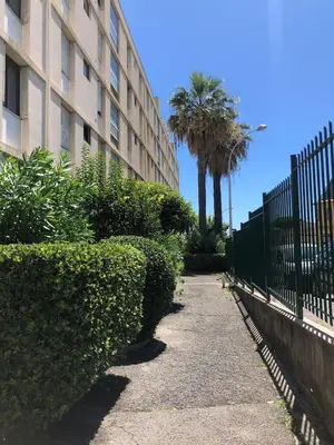 a sidewalk next to a building with a fence and palm trees at Big Apartement 20 min from beach in Nice