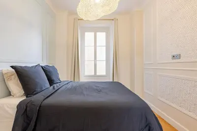 a bedroom with a bed and a window and a chandelier at Bella Nissa Bnb - AC wifi - cosy - 2 bedrooms in Nice
