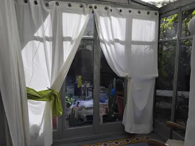 a window with white curtains in a room at Maison authentique in Nice