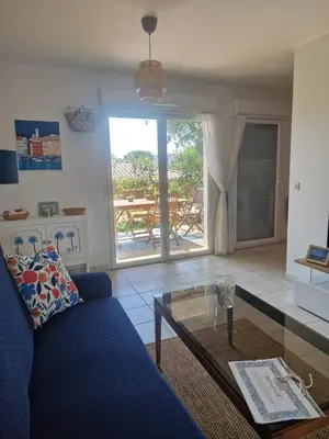 a living room with a blue couch and a glass table at Appartement 2 P calme in Cagnes-sur-Mer