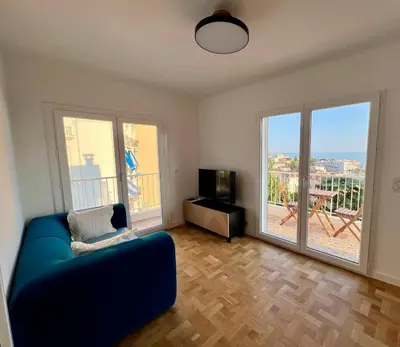 a living room with a blue couch and a balcony at Appartement Vue Mer T2 Cosy, Plage à pied 3 mins, Coucher de Soleil, Parc privé in Nice