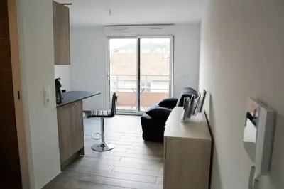 a living room with a black couch and a table at Studio climatisé au calme, mezzanine et balcon in Nice