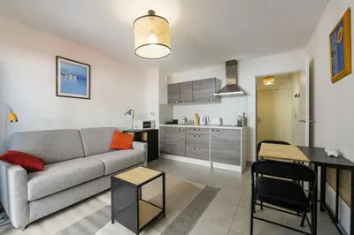 a living room with a couch and a kitchen at Studio au port de nice in Nice