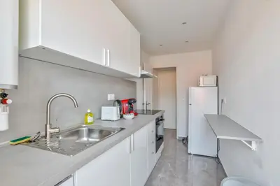 a white kitchen with a sink and a refrigerator at Magnifique studio en plein centre de Nice in Nice