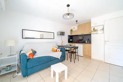 a living room with a blue couch and a kitchen at Studio port de Nice Clim Balcon in Nice