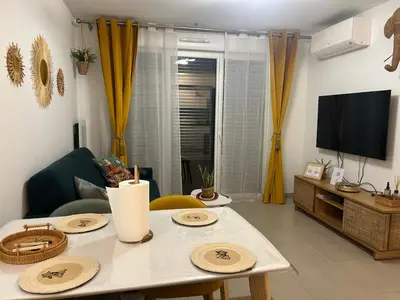 a living room with a table and a tv at Appartement neuf T2 calme avec terrasse - Proche Marché Liberation in Nice