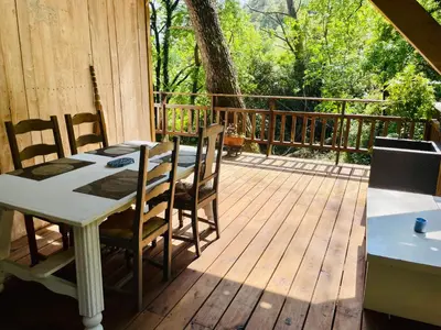 a tree house with a deck in the woods at Le chalet du Rêveur in La Gaude