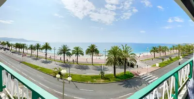 a view of a street with palm trees and the ocean at Le Milord - Easy Home Booking in Nice