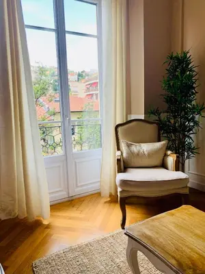 a living room with a chair and a large window at Cocon chic au cœur de la ville in Nice