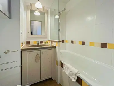 a bathroom with a sink and a tub and a mirror at Ange Gardien - AC, Parking, Piscine in Villefranche-sur-Mer