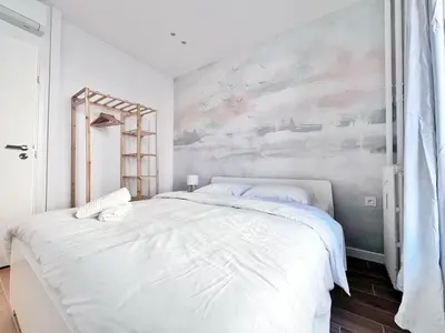 a bedroom with a large white bed with a painting on the wall at RF 121 Close to port 2 bedrooms 2 toilets in Nice