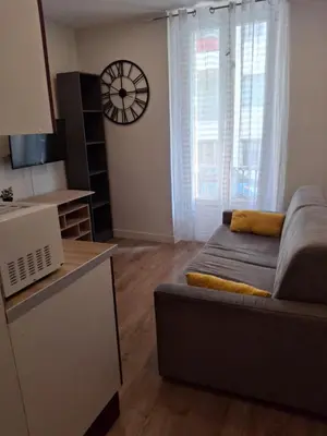 a living room with a bed and a clock on the wall at Studio 1 pièce in Nice