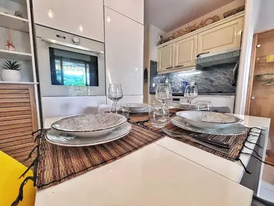a kitchen with plates and wine glasses on a counter at Rez de jardin privatif à 150m de la mer in Villefranche-sur-Mer