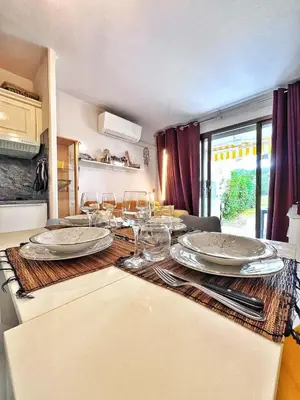 a table with plates and wine glasses on it at Rez de jardin privatif à 150m de la mer in Villefranche-sur-Mer
