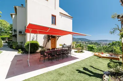 a patio with a table and chairs under a red umbrella at VILLA MONTE CRISTO - Villa conviviale a Nice - Superbe vue, piscine et jeux en plein air in Nice