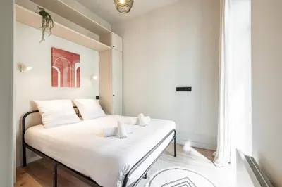 a bedroom with a bed with white sheets at 5 BEAUMONT - Magnifique 3P au style boheme - Quartier Garibaldi in Nice
